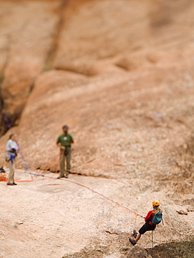 Woman in rappelling gear at top of cliff