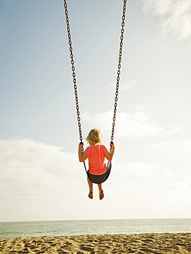 Girl (4-5) swinging on beach, San Clemente, California