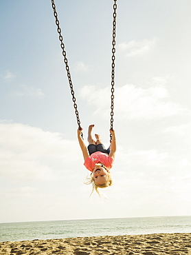 Girl (4-5) swinging on beach, San Clemente, California