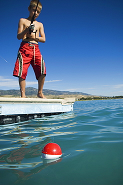 Boy fishing off dock in lake, Utah, United States