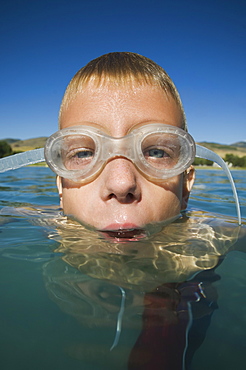 Boy wearing swimming goggles in water, Utah, United States