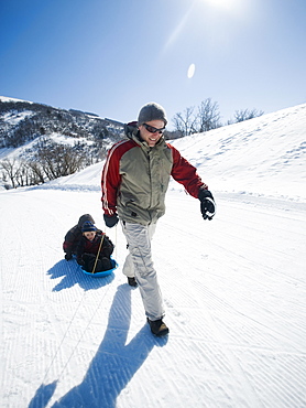 Father pulling children on sled