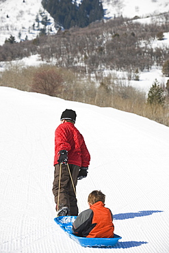 Boy pulling brother in sled