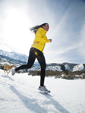 Woman and dog running in snow