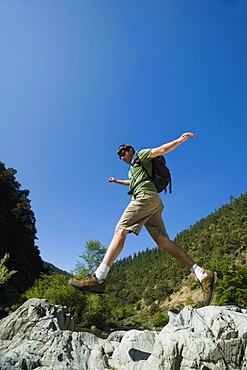 Hiker jumping across rocks