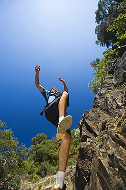 Hiker jumping down rocky trail