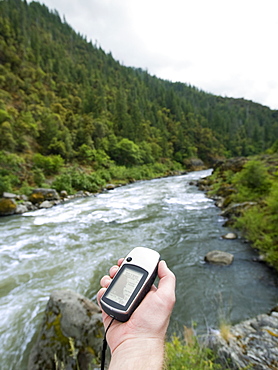 Man holding gps unit by river