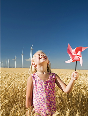 Smiling girl holding pinwheel on wind farm