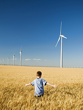 Boy running through field on wind farm