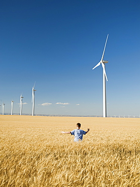 Boy running through field on wind farm