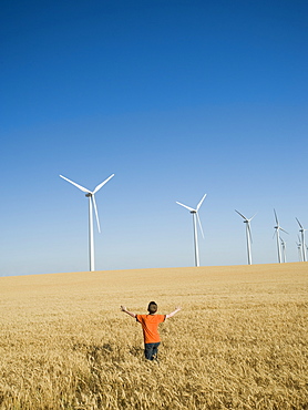 Boy standing in field on wind farm