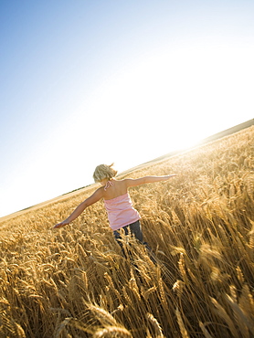 Girl running through tall wheat field