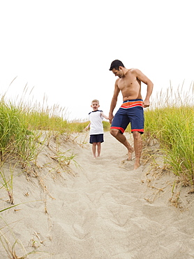 Father and son holding hands and running on beach