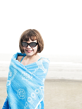 Portrait of girl in sunglasses wrapped in a towel on beach