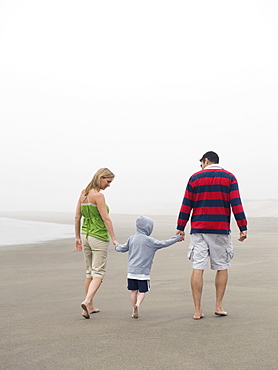 Parents holding hands with son on beach