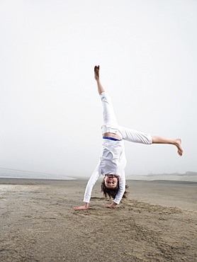 Portrait of girl doing handstand on beach