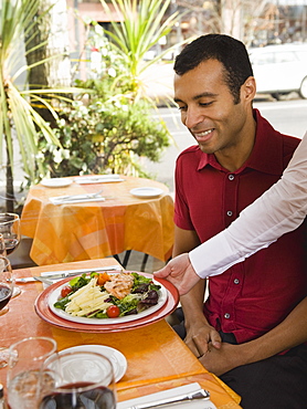 Waiter serving food to man in restaurant