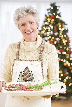 Senior woman holding tray of Christmas cookies