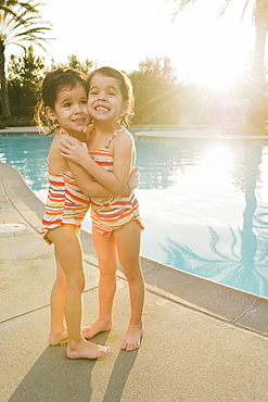 Sisters standing beside pool