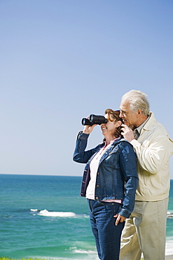 Couple looking at ocean with binoculars