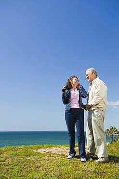 Couple looking at ocean with binoculars