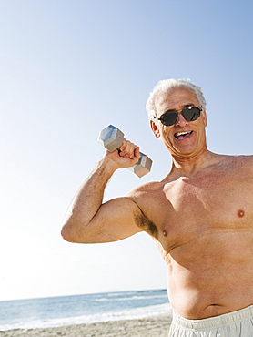 Man exercising with dumbbell on beach