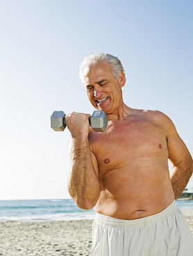 Man exercising with dumbbell on beach