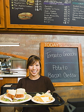 Woman holding tray of food in bakery