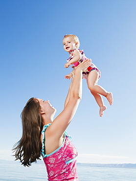 Mother with baby daughter (12-18months) playing on holidays