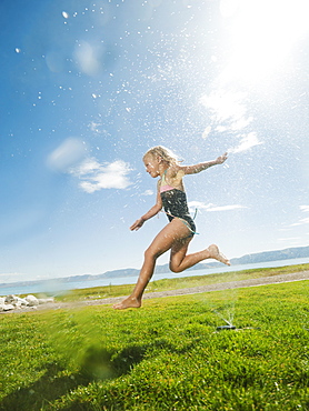 Girl (8-9) jumping over watering system