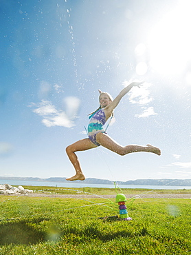 Girl (8-9) jumping over watering system