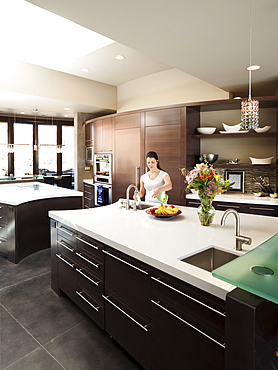 Young woman bustling around in modern domestic kitchen