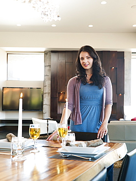 Young attractive woman standing behind table prepared for dinner