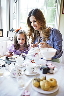 Mother and daughter (4-5) eating together in dining room