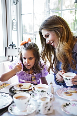 Mother and daughter (4-5) eating together in dining room