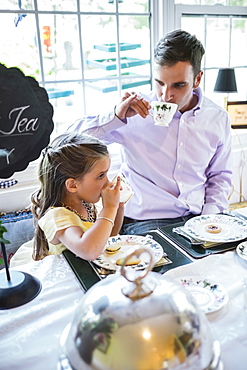 Father and daughter (4-5) eating together in dining room