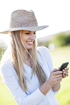 Portrait of smiling woman in straw hat using mobile phone