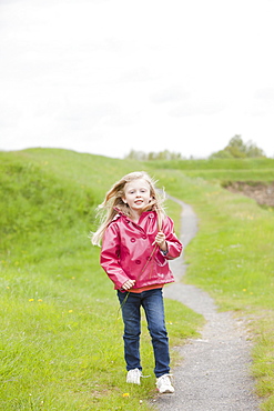 Girl in pink raincoat on country path, France, Rocroi