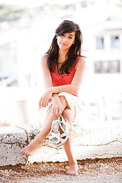 France, Cassis, Young woman sitting on stone wall, France, Cassis