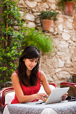 France, Cassis, Young woman using digital tablet in cafe, France, Cassis