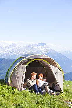 Switzerland, Leysin, Hikers resting in tent pitched on meadow, Switzerland, Leysin