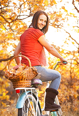 Happy young woman with bicycle in autumn in forest, Alpine, Utah