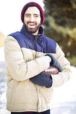 Portrait of man holding football outdoors