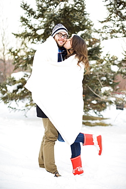 Couple wrapped in blanket standing in snow