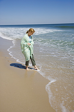 Woman wrapped in blanket at beach