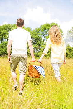 Couple walking with picnic basket on meadow, USA, New Jersey, Mendham