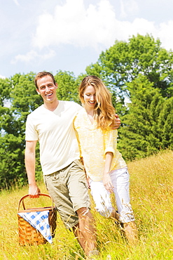 Couple walking with picnic basket on meadow, USA, New Jersey, Mendham