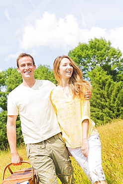 Couple walking with picnic basket on meadow, USA, New Jersey, Mendham