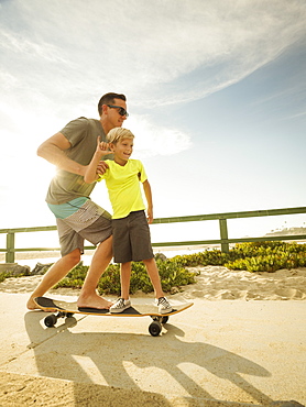 Father skateboarding with his son (6-7), Laguna Beach, California