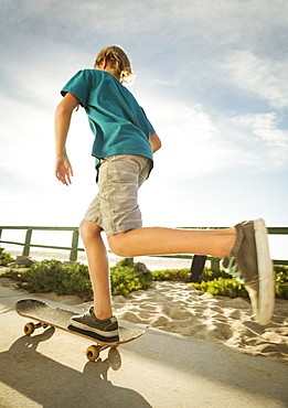 Teenage boy (14-15) skateboarding on path on beach, Laguna Beach, California